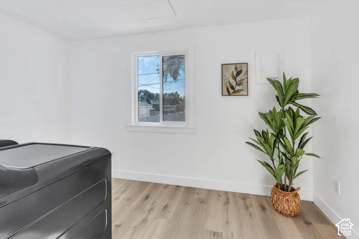 Room featuring wood-finish flooring, white walls, and a sliding window with white trim