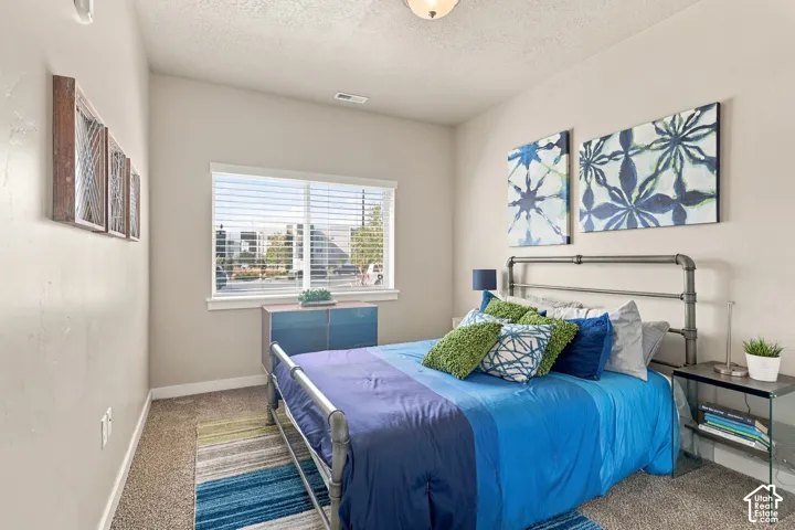 Neutral-toned interior room with wall-to-wall carpeting, high ceilings, and a large window featuring horizontal blinds and white trim