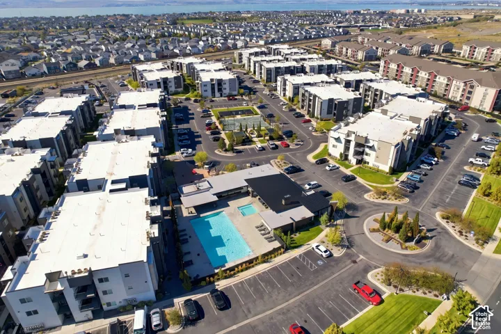 Aerial perspective of a multi-unit residential complex featuring a swimming pool, spa, sport court, and paved parking facilities