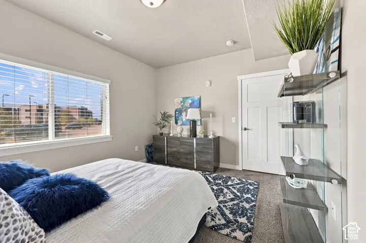 Room featuring wall-to-wall carpeting, large window with horizontal blinds, and a solid-core three-panel interior door