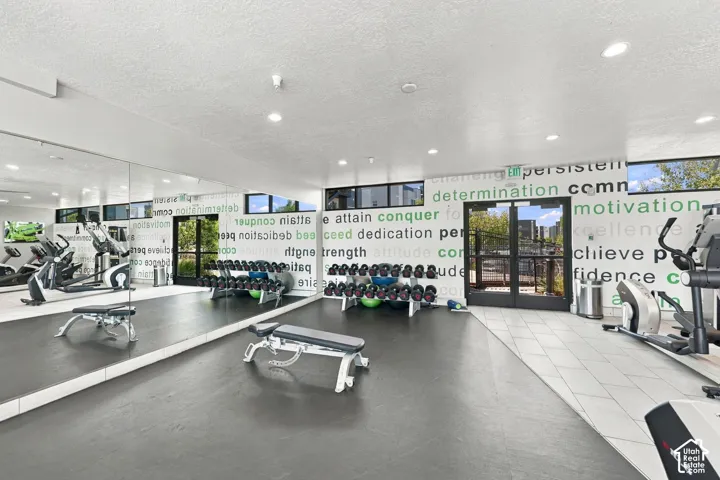 Fitness space featuring a full-wall mirror, recessed lighting, rubberized flooring, and horizontal windows