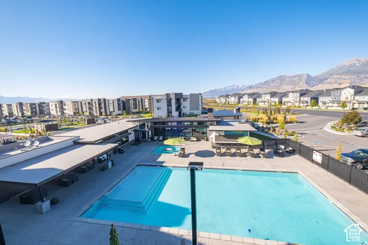 Outdoor pool area featuring concrete decking, a built-in spa, a covered pavilion, and mountain backdrops