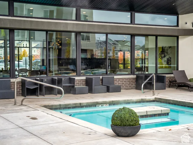 In-ground spa with concrete decking, brick masonry accents, large-pane windows, and stainless steel handrails