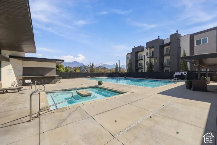 Community swimming pool and spa area featuring a concrete deck, built-in bar, and mountain backdrop