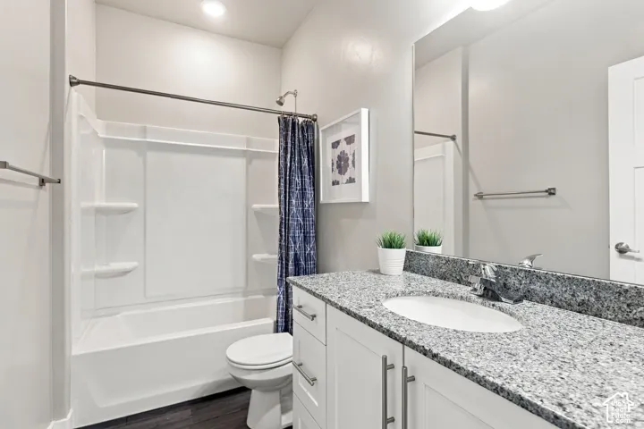 Bathroom featuring a white vanity with stone-patterned countertop, an integrated oval sink with a chrome faucet, a full-width vanity mirror, and a white tub-shower combination with built-in shelving