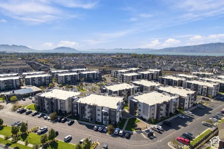 Aerial perspective of a multi-unit residential complex featuring flat roofs, modern siding, private balconies, paved surface parking, and extensive landscaping