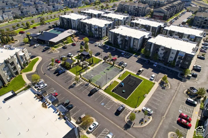Aerial view of a residential complex featuring a basketball court, playground area, swimming pool, and dedicated parking lots