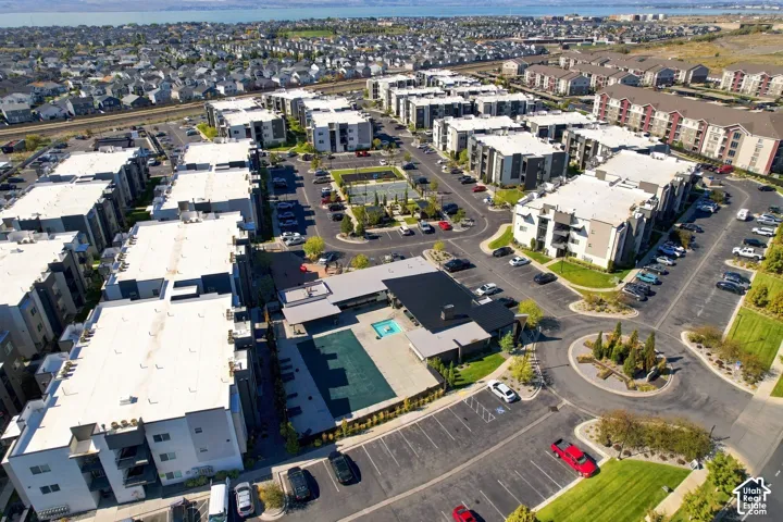 Aerial perspective of a multi-unit residential community featuring a centralized swimming pool, dedicated paved parking areas, and a recreation court