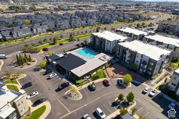 Multi-story residential complex featuring a community swimming pool, dedicated parking areas, and manicured landscaping
