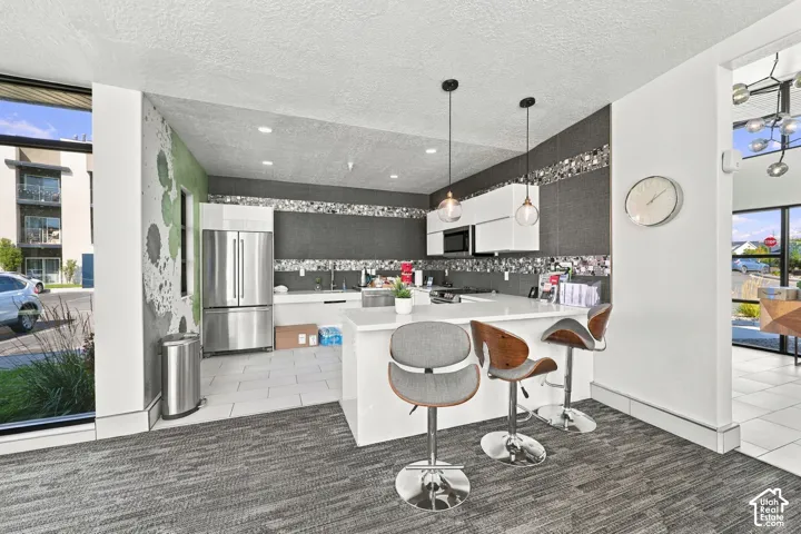Clubhoouse Kitchen featuring white cabinetry, quartz countertops, a stone-tile backsplash, stainless steel appliances, and pendant lighting