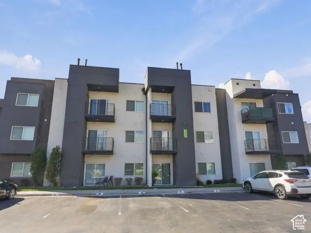 Contemporary multi-story exterior featuring a two-tone stucco facade, recessed balconies with metal railings, and dual-pane windows