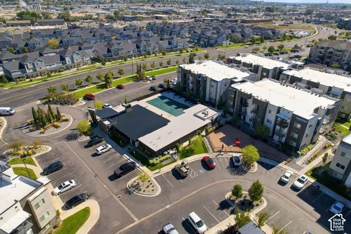 Aerial perspective featuring a multi-story residential building with an outdoor swimming pool, paved surface parking, and curated landscape islands