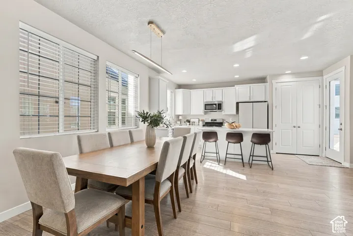 Kitchen area featuring white cabinetry, quartz-surface breakfast bar, wood-finish flooring, recessed lighting, and a linear pendant fixture