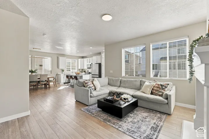 Open-concept interior featuring light-toned wood-finish flooring, recessed lighting, and a white fireplace surround