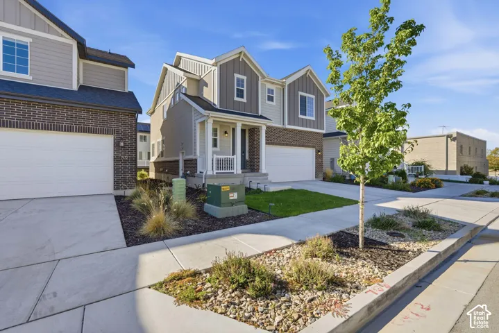Multi-level exterior featuring a brick and composite siding facade, covered front porch, and an attached two-car garage