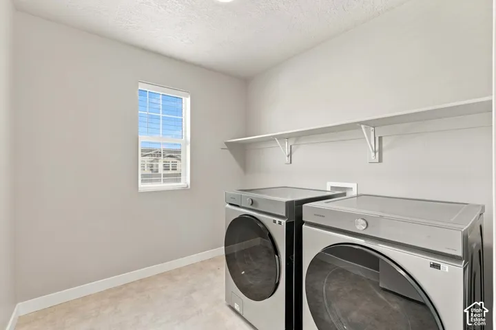 Laundry space featuring a single-hung window, wall-mounted shelving, and hard-surface flooring