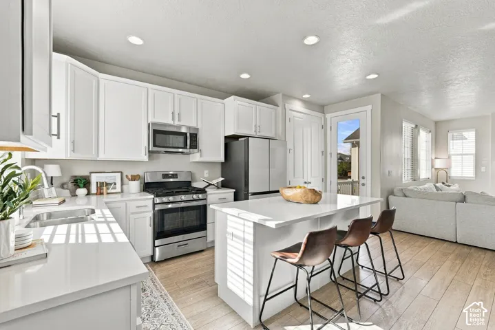 Kitchen featuring white cabinetry, stone-surface countertops, center island, recessed lighting, and wood-finish flooring