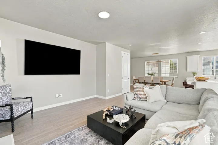 Open-concept interior featuring light wood-finish flooring, neutral wall tones, recessed lighting, and large windows