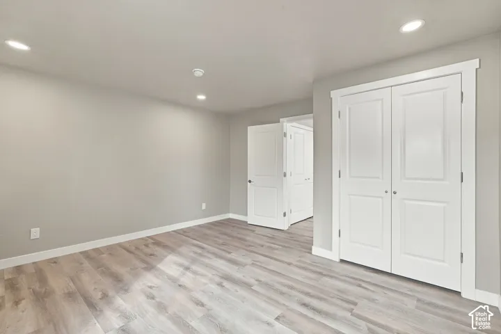 Wood-finish flooring, recessed lighting, and white shaker-style interior doors
