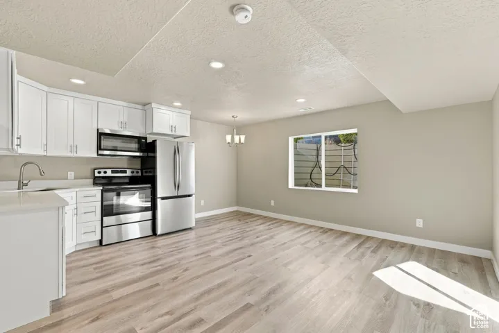 Kitchen featuring white cabinetry, light-toned countertops, stainless steel appliances, recessed lighting, and wood-finish flooring