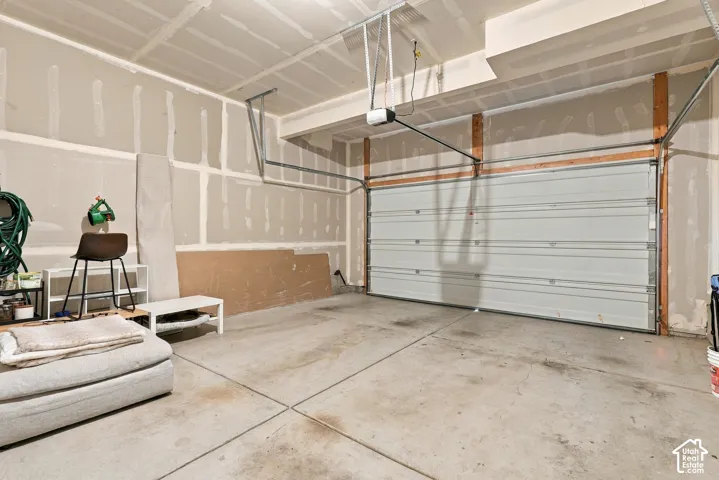 Two-car garage featuring a sectional overhead door, concrete flooring, and an automated garage door opener