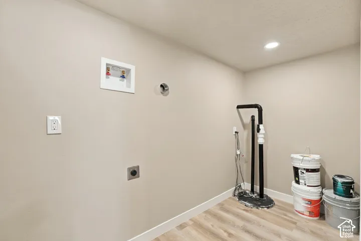 Utility space featuring recessed ceiling lighting, wood-finish flooring, integrated plumbing connections, and a sump pump system