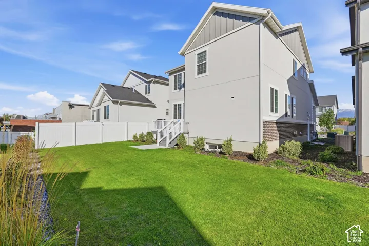 Exterior featuring a stucco and brick facade, a fenced-in yard, a manicured lawn, and a raised composite deck