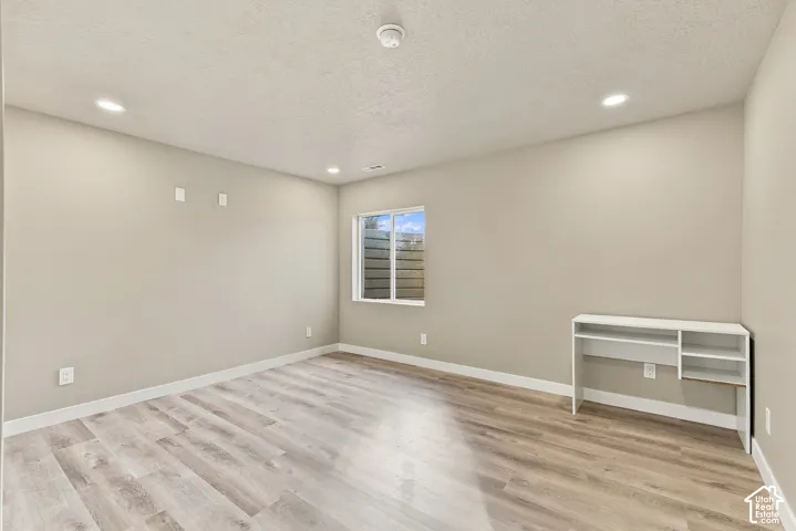 Interior space featuring wood-finish flooring, recessed lighting, neutral wall tones, and a built-in desk