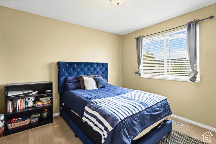 Neutral-toned bedroom featuring carpeting and a window with horizontal blinds