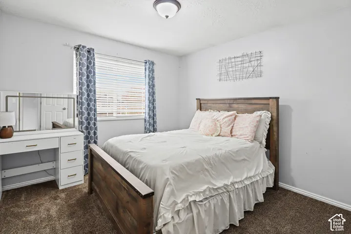 Bedroom featuring wall-to-wall carpeting, a dual-pane window with horizontal blinds, and a centered flush-mount ceiling light fixture