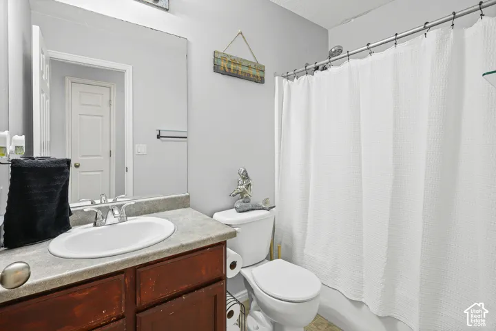 Full-width vanity with a neutral solid-surface countertop, oval undermount sink, and polished chrome faucet, paired with a shower-tub combination featuring a chrome showerhead and a large-format vanity mirror