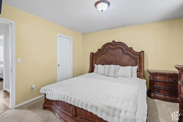 Bedroom featuring neutral wall paint, wall-to-wall carpeting, a multi-panel interior door, and a ceiling-mounted flush-mount light fixture