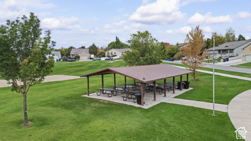 Open-air pavilion featuring a metal roof, concrete slab foundation, and mature landscaping