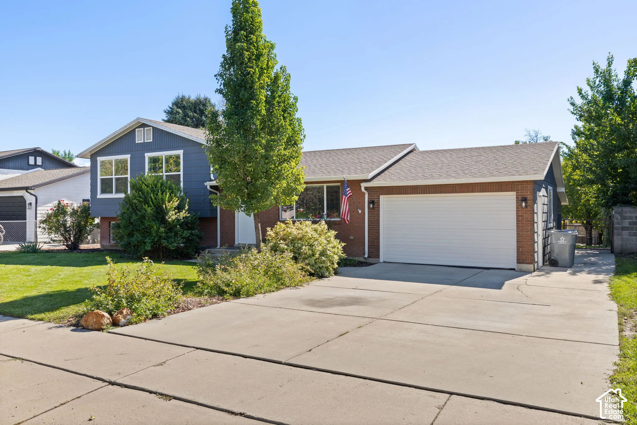 Split-level exterior featuring a combination of red brick and horizontal siding, an attached two-car garage, and a concrete driveway