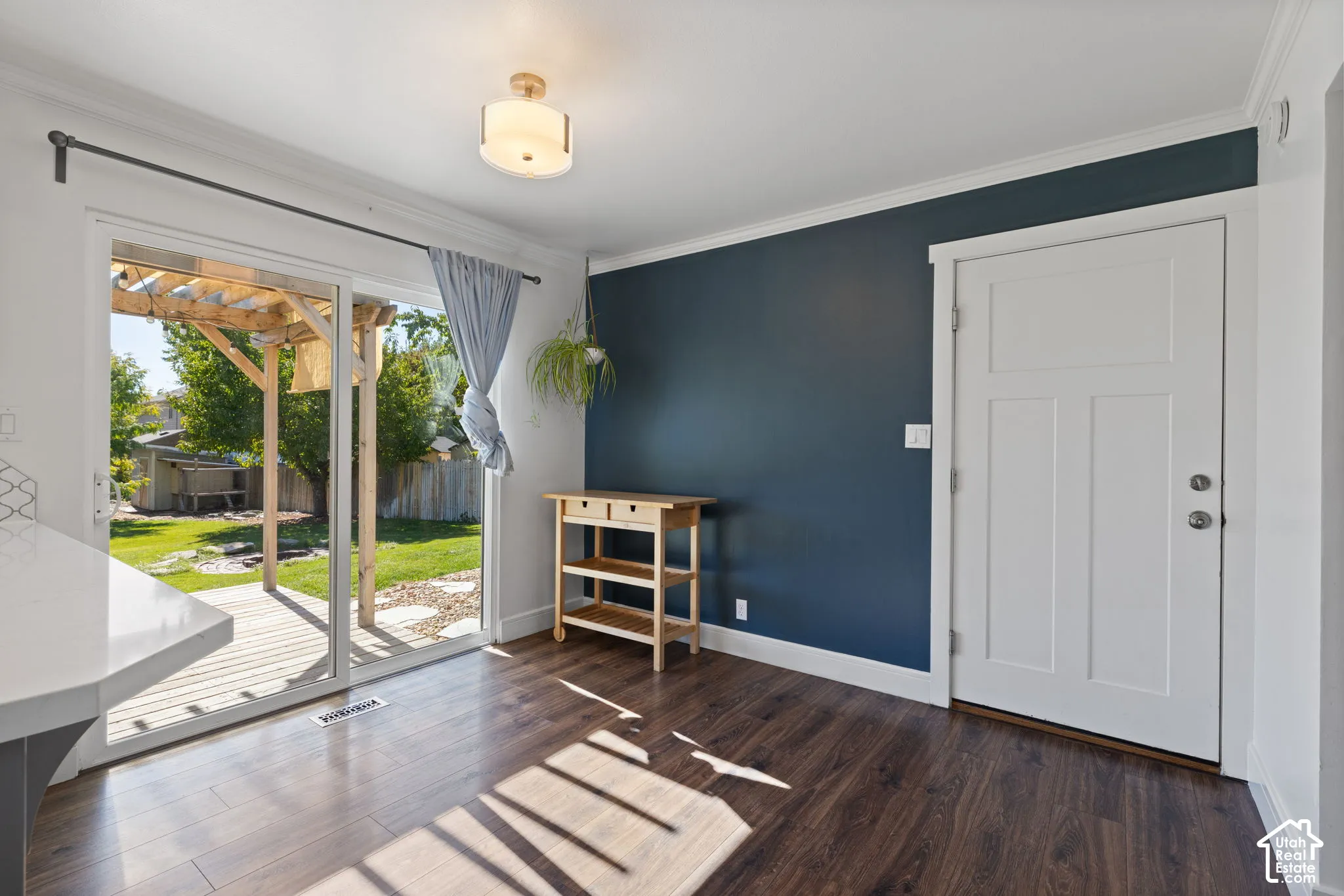 Sliding glass doors providing exterior access, wood-finish flooring, accent wall, and a flush-mount ceiling light fixture