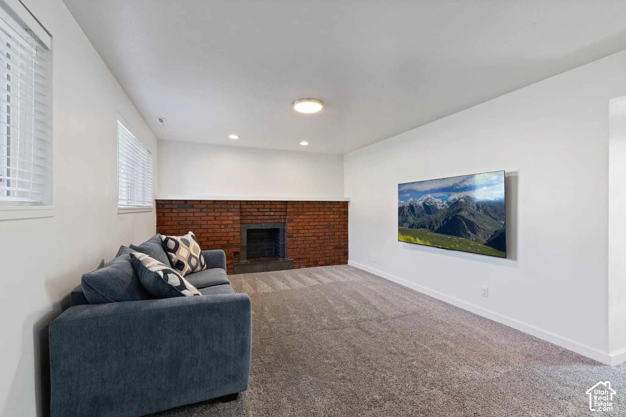 Room interior featuring a red brick fireplace, recessed lighting, carpeted flooring, and white walls