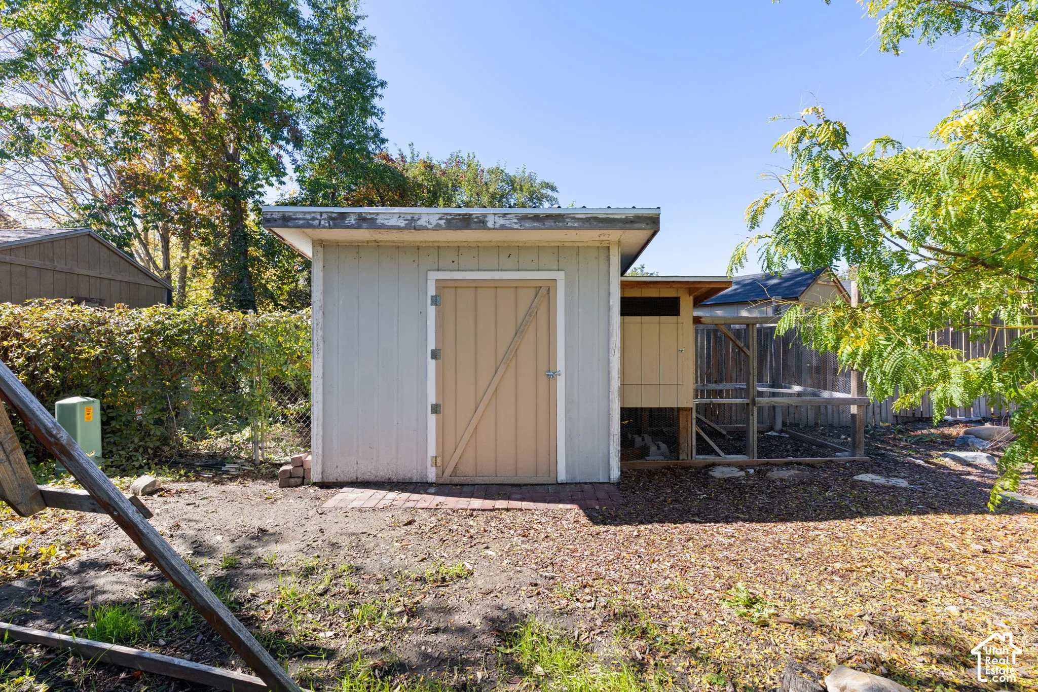 Exterior storage structure with a shed-roof design, a solid access door, and an attached wire-mesh enclosure