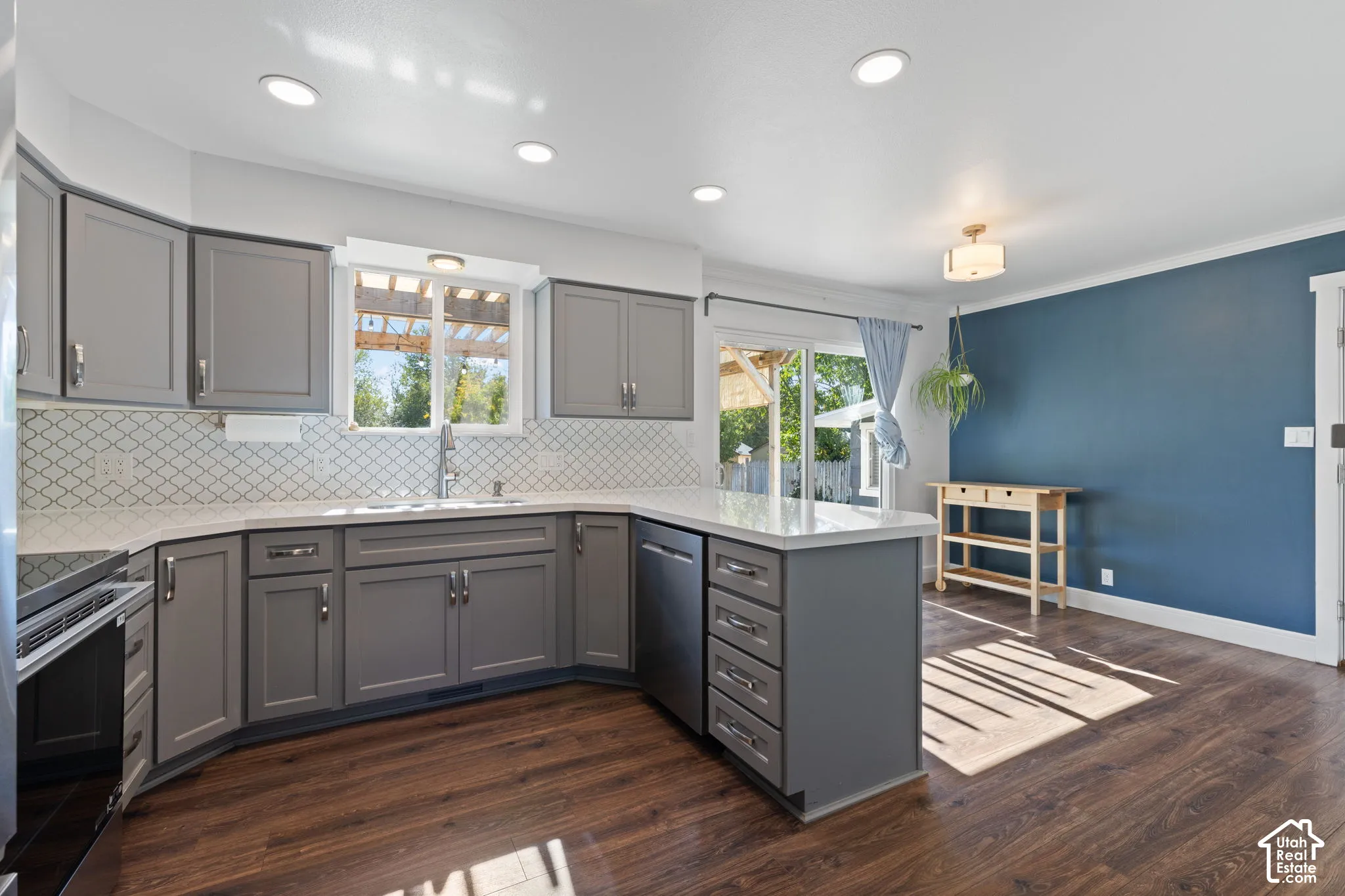 Kitchen featuring gray shaker-style cabinetry, white quartz countertops, geometric tile backsplash, recessed lighting, and wood-finish flooring