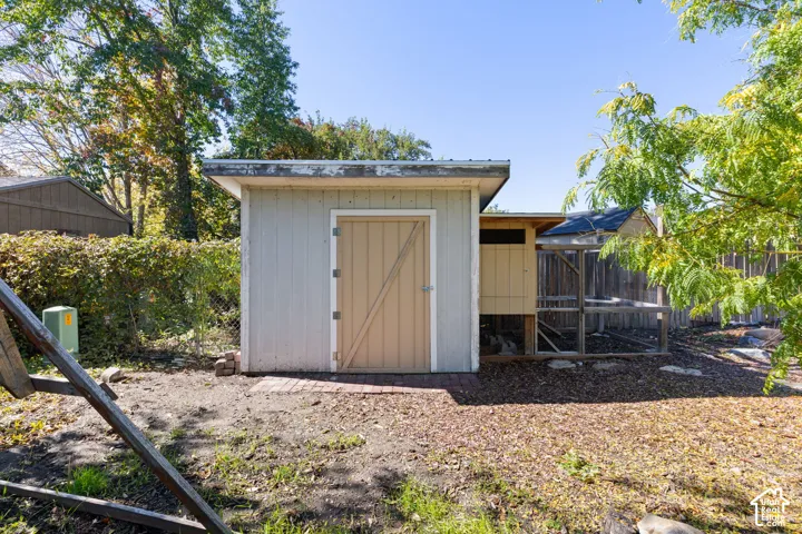 Exterior storage structure with a shed-roof design, a solid access door, and an attached wire-mesh enclosure