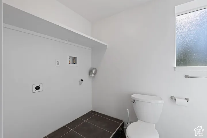 Utility space featuring tile flooring, built-in shelving, plumbing hookups, and a privacy-glass window