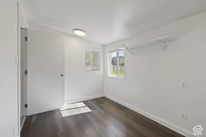 Interior space featuring wood-finish flooring, dual windows with blinds, a flush-mount ceiling light, and built-in wall shelving