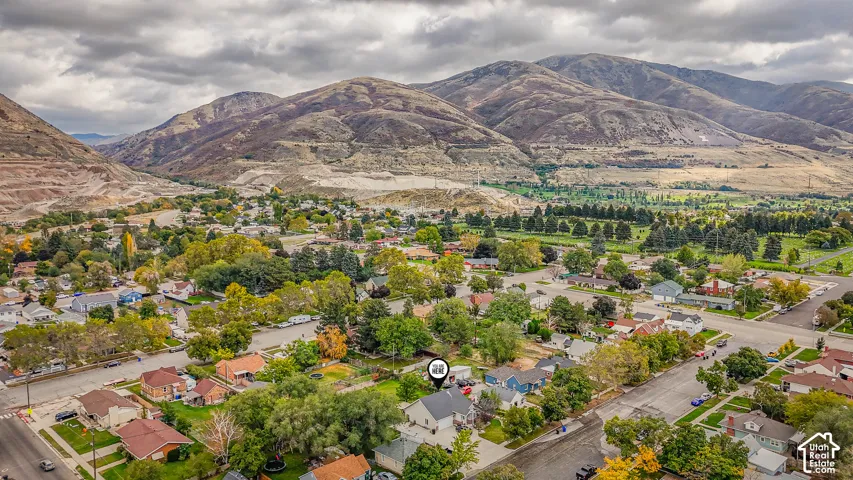 Aerial perspective featuring a single-family residence with an attached garage, positioned against a backdrop of prominent mountain ranges and expansive hills