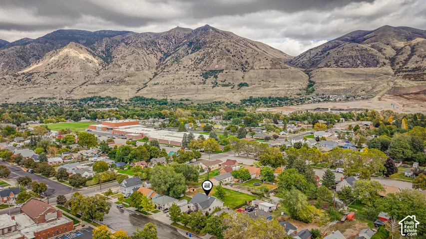 Aerial perspective featuring an established neighborhood setting with mountain range backdrop and mature trees