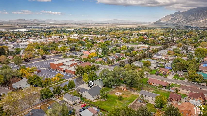 Aerial perspective showcasing the property location, established neighborhood infrastructure, mature trees, and mountainous backdrop