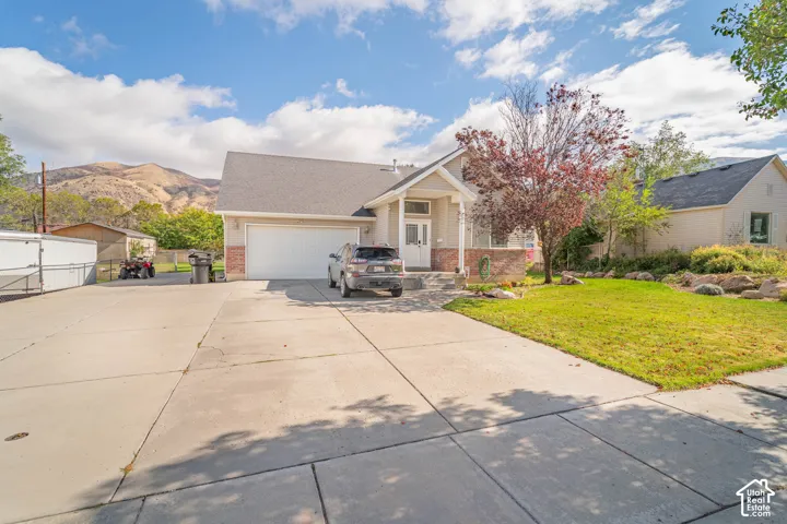 Single-story residence featuring brick and siding exterior, concrete driveway, attached garage, and mountain backdrop