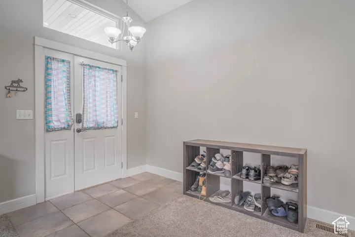 Entryway featuring double doors with glass inserts, a transom window, a vaulted ceiling, and tile flooring