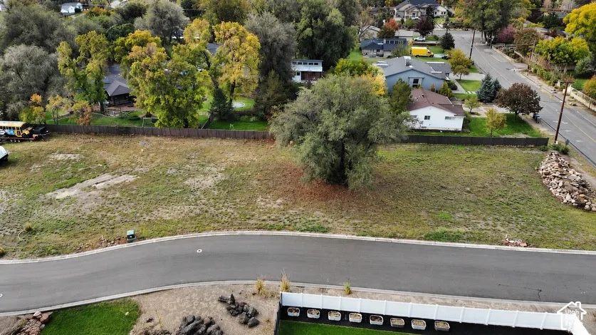 Expansive corner lot featuring mature trees, a perimeter fence, and direct street access