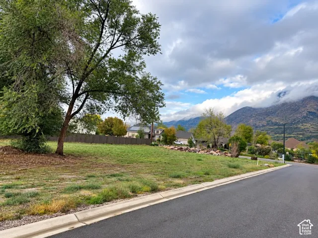 Vacant corner lot featuring mature trees, natural rock outcroppings, paved street access, and mountain surroundings