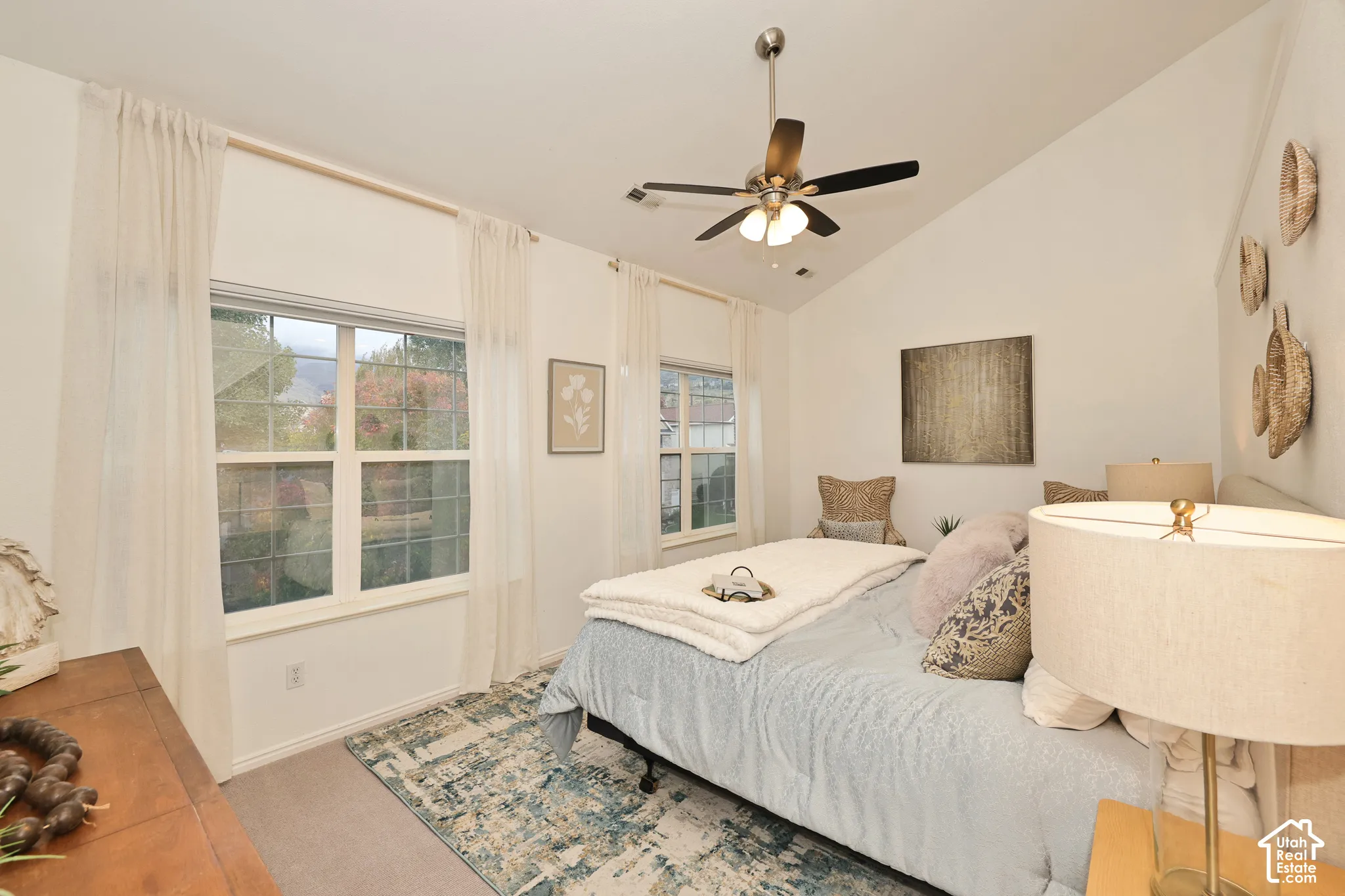 Vaulted ceiling featuring a central brushed-nickel ceiling fan with integrated lighting and dual grid-pane windows