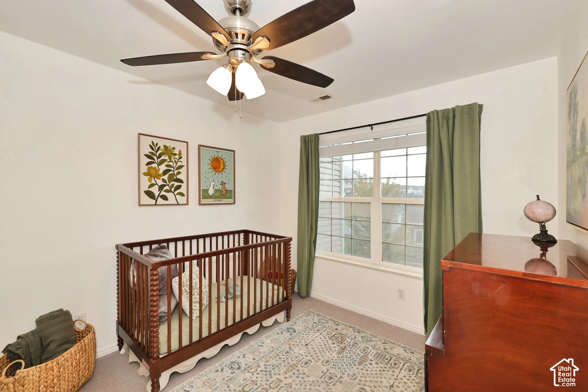 Neutral-toned bedroom featuring wall-to-wall carpeting, a multi-blade ceiling fan with integrated lighting, and a multi-pane window with grid detailing